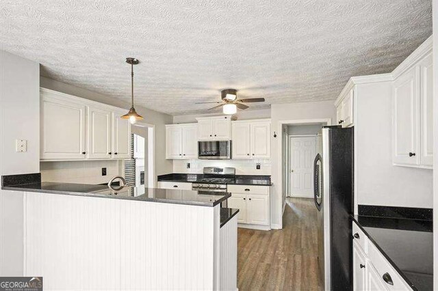 802 Eagle Glen Xing, Woodstock, GA 30189 - kitchen featuring stainless steel appliances, dark countertops, a peninsula, ceiling fan, and white cabinetry