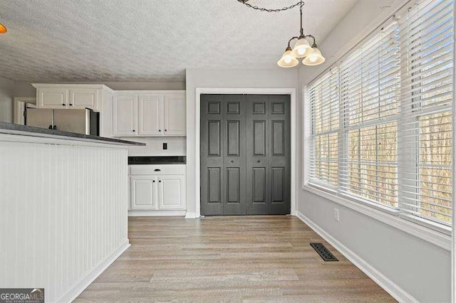 802 Eagle Glen Xing, Woodstock, GA 30189 - unfurnished dining area with a chandelier, light wood-type flooring, and a textured ceiling