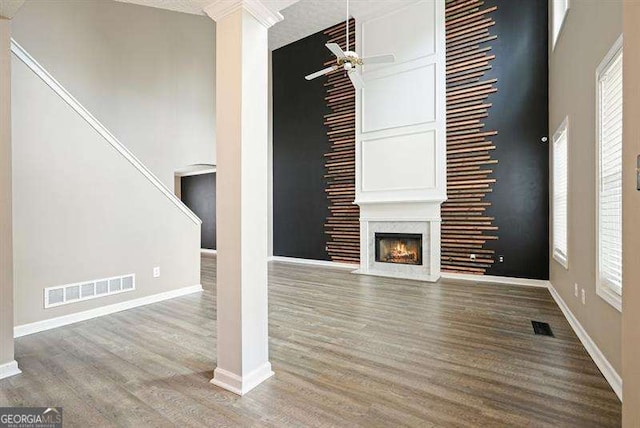 802 Eagle Glen Xing, Woodstock, GA 30189 - unfurnished living room with a ceiling fan, wood finished floors, a fireplace with flush hearth, stairway, and a high ceiling
