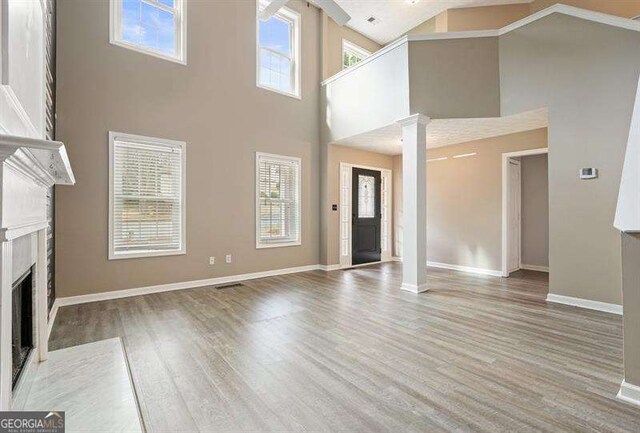 802 Eagle Glen Xing, Woodstock, GA 30189 - unfurnished living room featuring a high ceiling, a fireplace with flush hearth, wood finished floors, plenty of natural light, and ornate columns