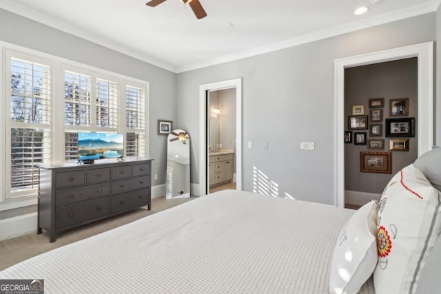 carpeted bedroom featuring crown molding, baseboards, ceiling fan, and ensuite bath