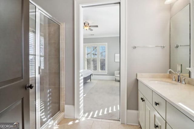 ensuite bathroom featuring a shower stall, a ceiling fan, vanity, and baseboards
