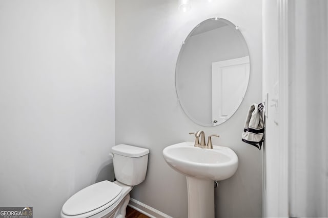 half bathroom with toilet and baseboards