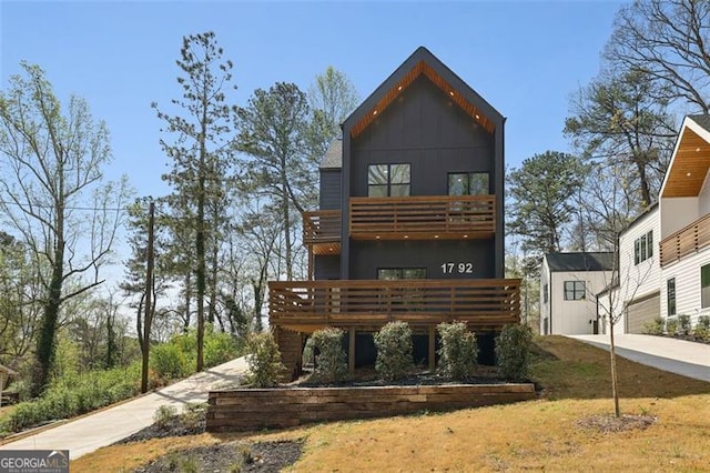rear view of house with board and batten siding, a balcony, and concrete driveway