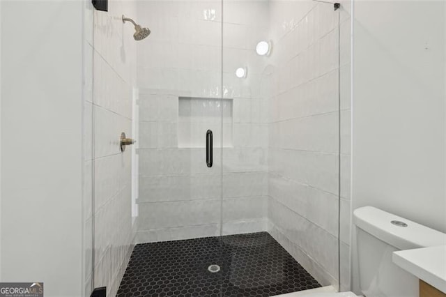 bathroom featuring toilet and a stall shower