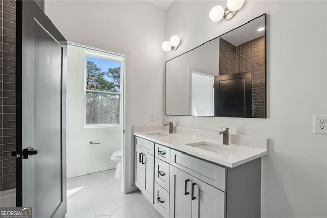 full bath featuring double vanity, a sink, toilet, and tile patterned flooring