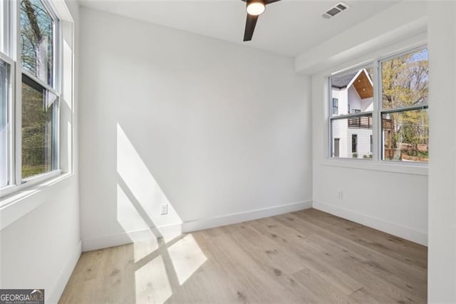 empty room featuring visible vents, wood finished floors, and a healthy amount of sunlight