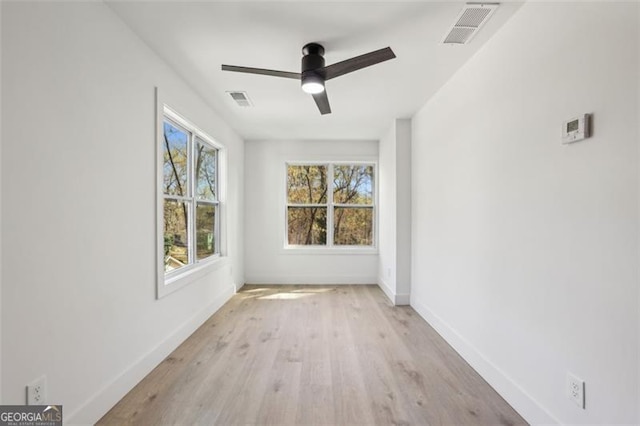 empty room featuring a ceiling fan, wood finished floors, baseboards, and visible vents