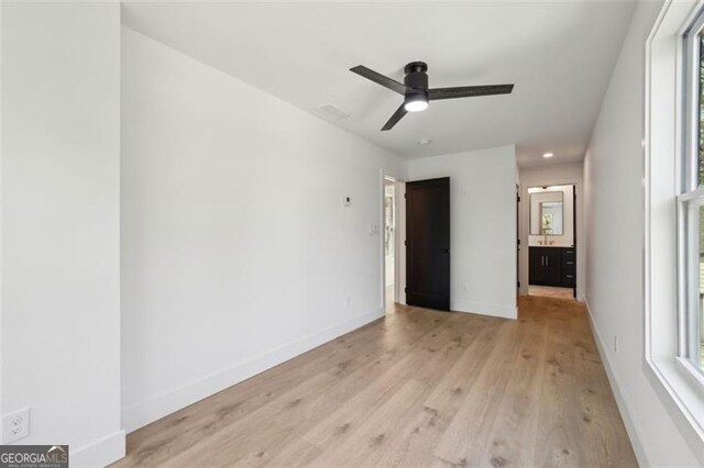 unfurnished bedroom with baseboards, ensuite bath, and light wood finished floors