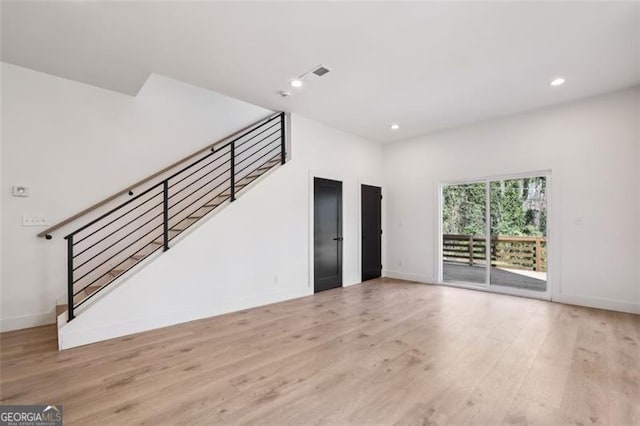 unfurnished living room featuring baseboards, recessed lighting, wood finished floors, and stairway