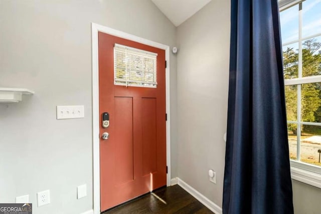 foyer entrance featuring dark wood-style floors, baseboards, and vaulted ceiling