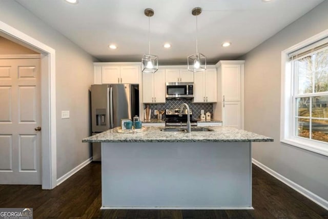 kitchen with a sink, white cabinetry, a center island with sink, stainless steel appliances, and decorative backsplash