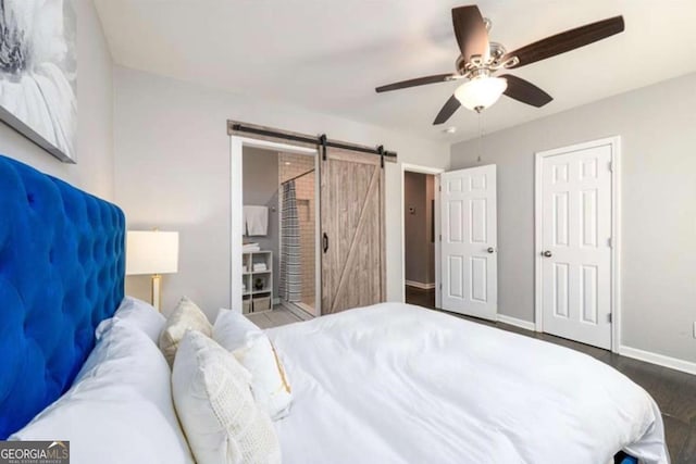 bedroom with baseboards, a barn door, wood finished floors, and a ceiling fan