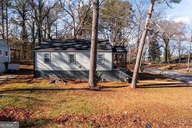 view of side of home featuring a lawn and a chimney