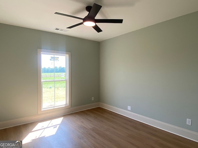 unfurnished room with visible vents, dark wood-style flooring, and baseboards