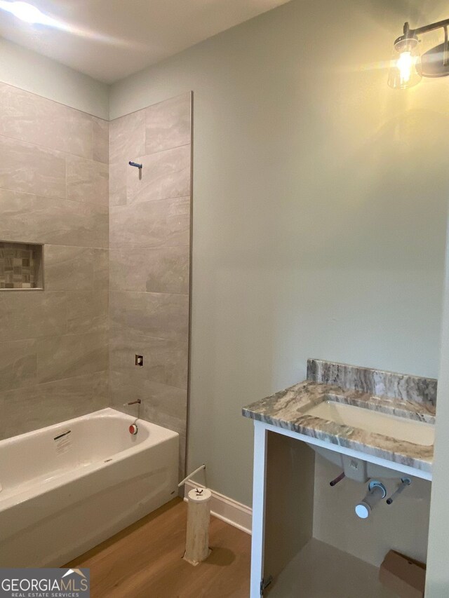 full bathroom with baseboards, wood finished floors, and tub / shower combination