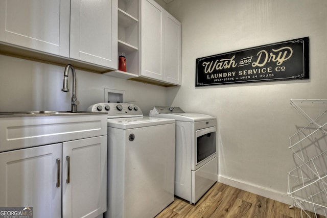 laundry area featuring washing machine and clothes dryer, baseboards, a sink, light wood-style floors, and cabinet space