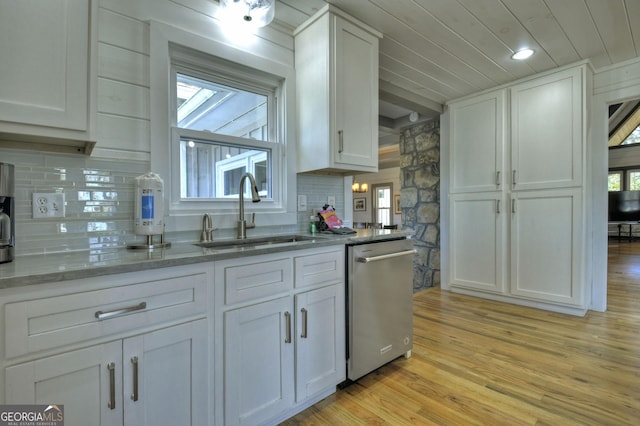 kitchen with light wood-style flooring, dishwasher, light stone countertops, white cabinetry, and a sink