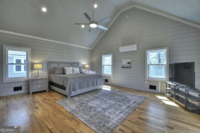 bedroom with multiple windows, visible vents, an AC wall unit, and wood finished floors