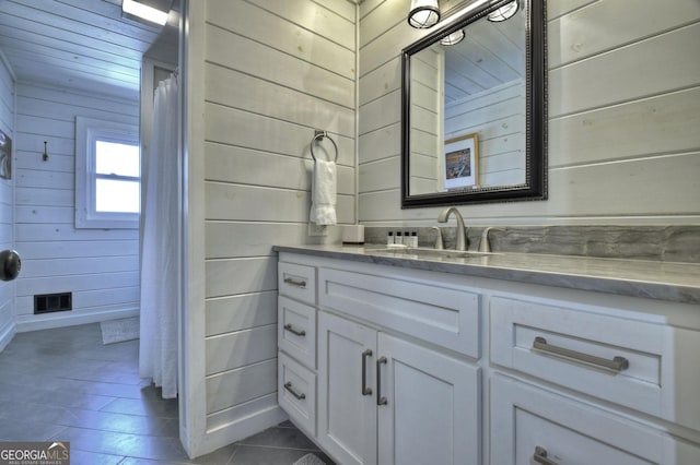 full bath with tile patterned floors, vanity, wood walls, and visible vents