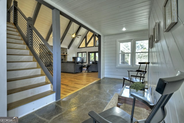 interior space with wood ceiling, a ceiling fan, vaulted ceiling with beams, a fireplace, and wood walls
