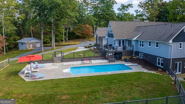 view of swimming pool featuring fence, a lawn, and a patio