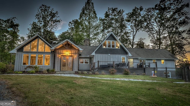 view of front facade with a chimney, a front yard, fence, and board and batten siding