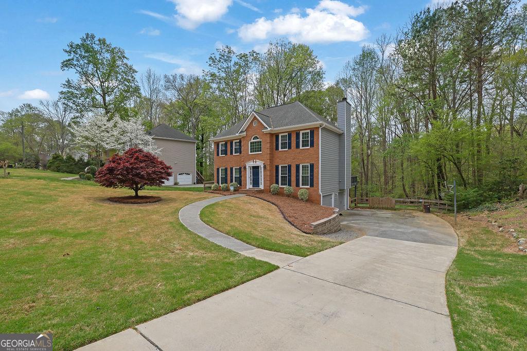 4495 Sagebrush Dr NW, Kennesaw, GA 30152 - colonial house with a chimney, a garage, concrete driveway, brick siding, and a front lawn