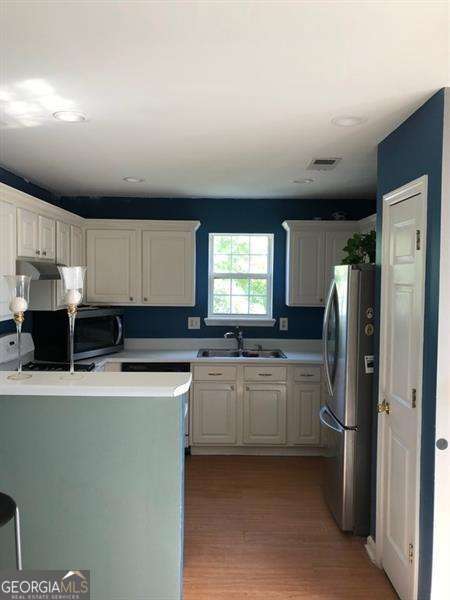 4528 Baker Grove Rd NW, Acworth, GA 30101 - kitchen with freestanding refrigerator, light countertops, light wood-style floors, white cabinets, and recessed lighting