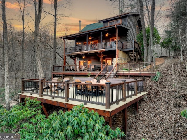 back of property with stairway, a deck, and metal roof