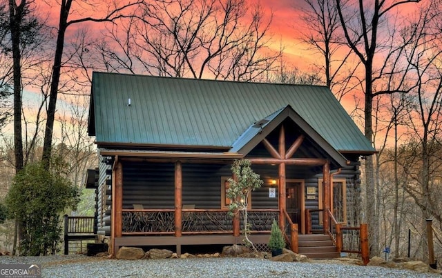 log home with log siding, metal roof, and a porch