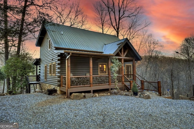 view of front of house featuring log siding, metal roof, and a porch