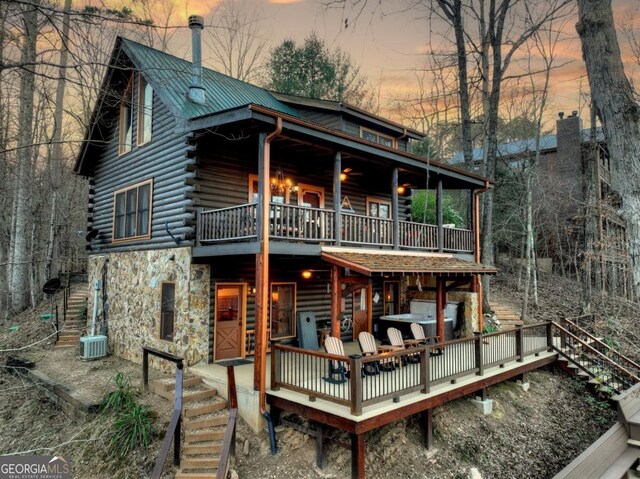 view of front facade with log siding, stairs, stone siding, and central air condition unit