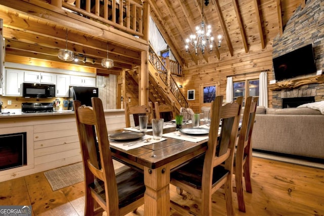 dining area with light wood-type flooring, a fireplace, wood walls, and wooden ceiling