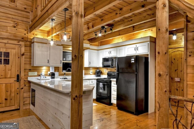 kitchen with light wood finished floors, black appliances, beam ceiling, and wood walls