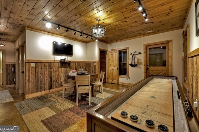 playroom featuring rail lighting, wood walls, a chandelier, a wainscoted wall, and wood ceiling