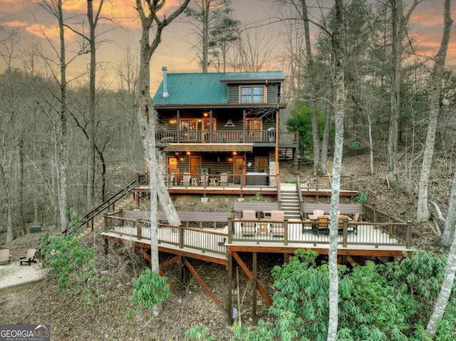 back of house at dusk with metal roof and a deck
