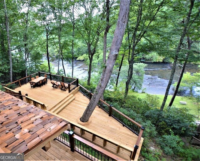 wooden terrace featuring a water view and a wooded view
