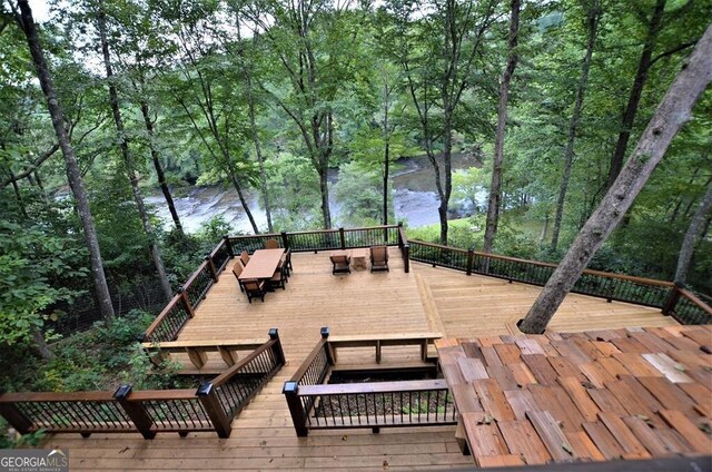 wooden deck featuring a water view and a view of trees