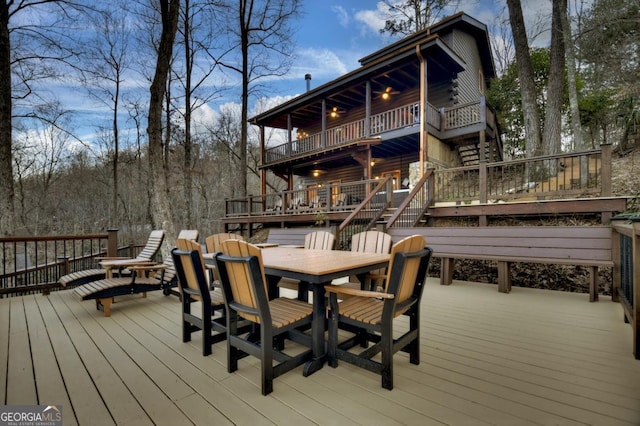 wooden terrace featuring outdoor dining space and stairway