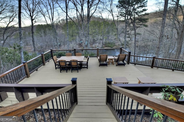 deck with outdoor dining area and a wooded view
