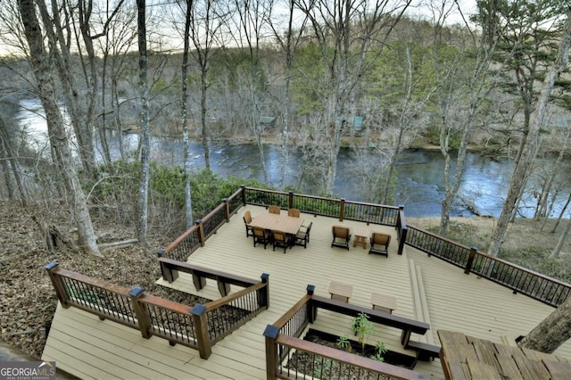 deck with a water view and outdoor dining space