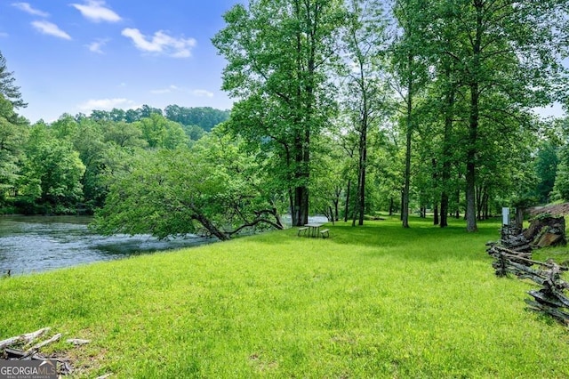 view of yard featuring a forest view and a water view