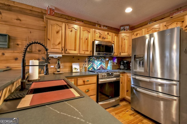 1301 Newport Dr, Ellijay, GA 30540 - kitchen with stainless steel appliances, a sink, a textured ceiling, light wood finished floors, and dark countertops