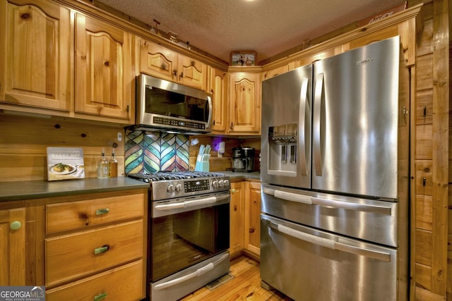 1301 Newport Dr, Ellijay, GA 30540 - kitchen featuring stainless steel appliances, dark countertops, decorative backsplash, light wood finished floors, and a textured ceiling