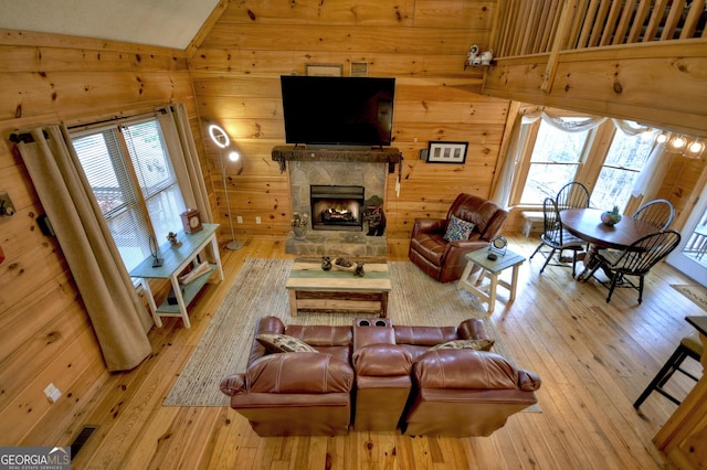 1301 Newport Dr, Ellijay, GA 30540 - living room with vaulted ceiling, wooden walls, healthy amount of natural light, wood-type flooring, and a stone fireplace