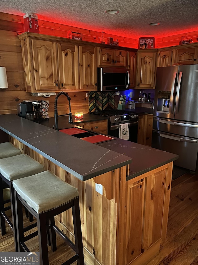 1301 Newport Dr, Ellijay, GA 30540 - kitchen with stainless steel appliances, dark countertops, a peninsula, wood finished floors, and a textured ceiling