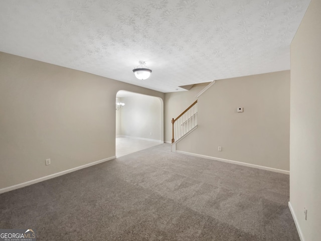 1005 Magnolia Gardens Walk, Mcdonough, GA 30253 - unfurnished room featuring a textured ceiling, baseboards, stairway, arched walkways, and carpet floors