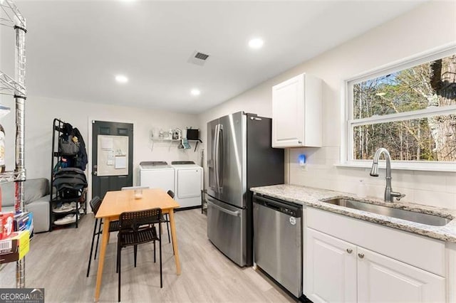 2374 Buchanan Hwy, Dallas, GA 30157 - kitchen with appliances with stainless steel finishes, white cabinetry, a sink, washer and dryer, and light stone counters