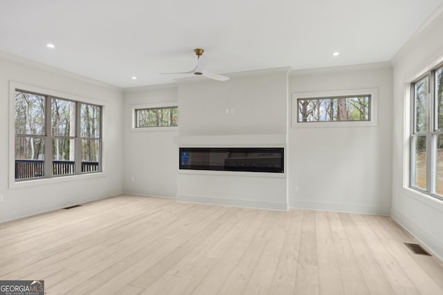 unfurnished living room featuring visible vents, wood finished floors, a glass covered fireplace, and a ceiling fan